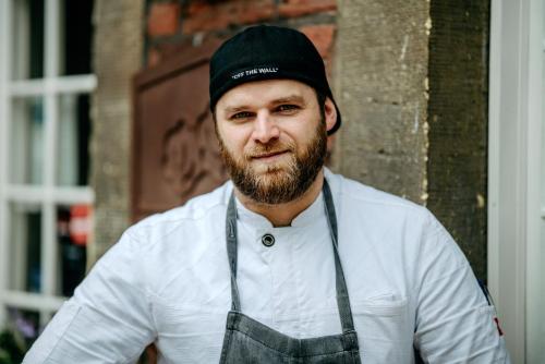 a man with a beard wearing a hat and apron at Romantik Hotel Hof zur Linde in Münster