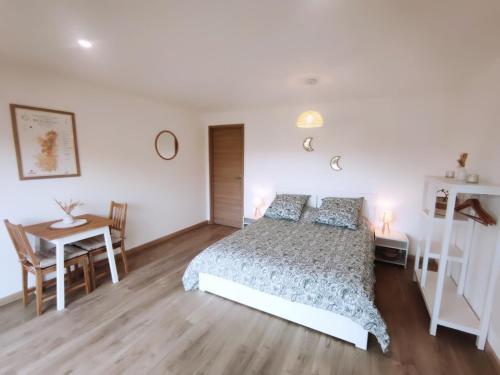 a bedroom with a bed and a table and a desk at Au creux du nid in Lamure-sur-Azergues