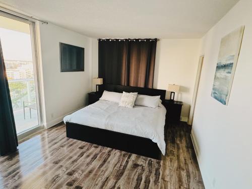 a bedroom with a bed and a large window at Miami Hallandale Condo, Partial Ocean View Direct Beach and Pool Access Miami Hollywood Beach in Hollywood