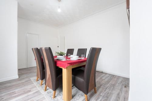 a dining room with a red table and black chairs at Spacious 5 bedroom house in Rochdale