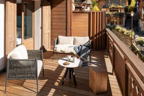 a wooden deck with two chairs and a table at Coeur de Megève in Megève