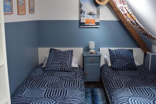 Dos camas en una habitación con paredes azules. en Les Girouteaux Le Fenil, en Les Eyzies-de-Tayac