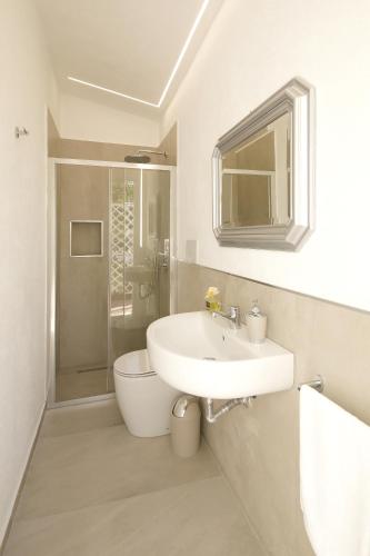 a bathroom with a sink and a toilet and a shower at Villa Merilusi Apartments in Fontane Bianche