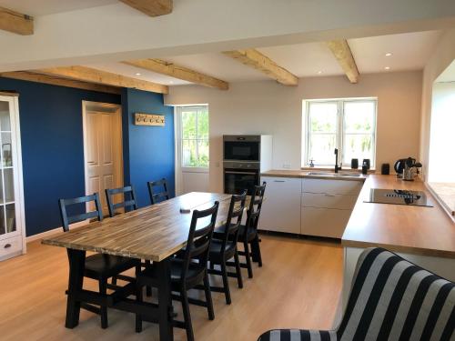 Una cocina y un comedor con mesa y sillas de madera. en Solhjem Bornholm - sea view - big garden, en Gudhjem