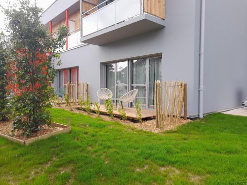 a house with a green yard with chairs and a tree at The Originals City, Ara Hôtel, Landerneau in Landerneau
