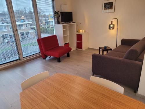 a living room with a couch and a red chair at Bright room with kitchen in Amsterdam