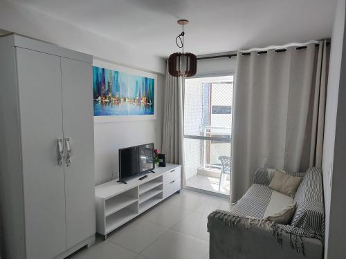 een woonkamer met een tv en een bank bij Apto Privado no Edifício Helbor My Way Abolição in Fortaleza