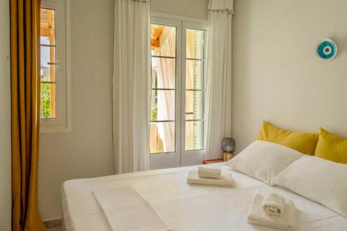 een slaapkamer met een wit bed met twee handdoeken erop bij Little Summer House in Toploú