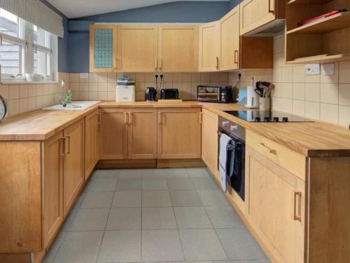 a large kitchen with wooden cabinets and appliances at Anvil House, Golspie in Golspie