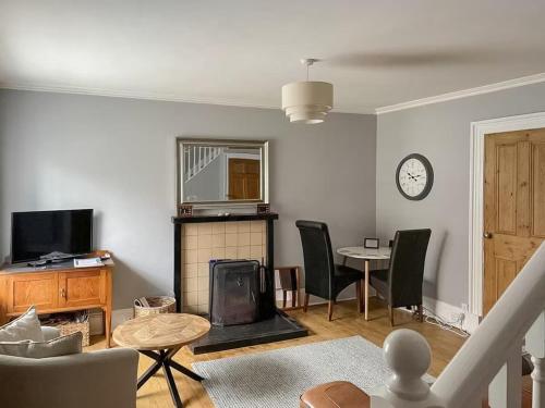 a living room with a fireplace and a table and chairs at Anvil House, Golspie in Golspie