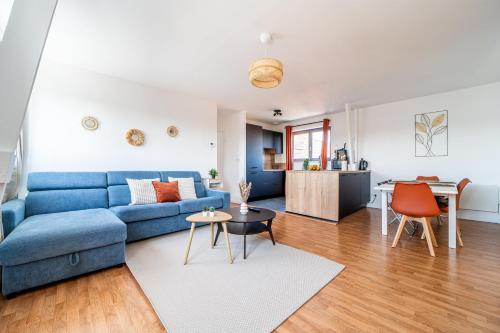 a living room with a blue couch and a kitchen at Le Saint-Jean - Hypercentre - Parking privé - 1 à 6 personnes - Wifi in Roubaix