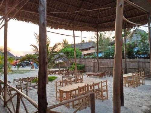 a beach with tables and chairs on the sand at Ndiro Beach House Kendwa in Kendwa