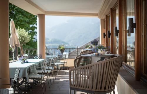 a restaurant with tables and chairs on a balcony at Taubers Unterwirt Aktiv & Vitalhotel in Feldthurns
