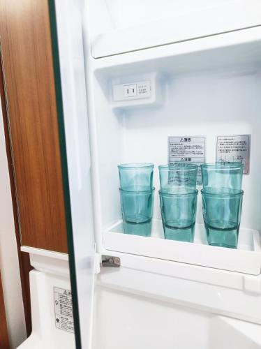 a refrigerator filled with blue glasses sitting inside at 駅近4分 富士山を眺める和風宿 in Gotemba