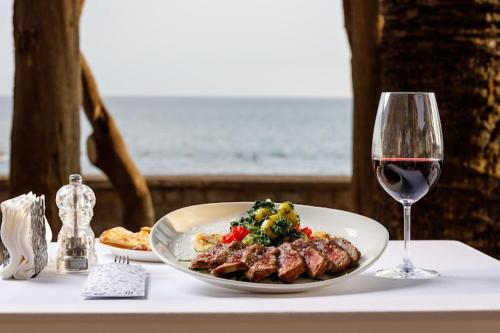 a plate of food and a glass of wine on a table at Sunraf Luxe Apartments in Budva