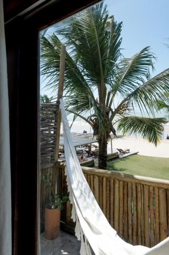 a hammock in front of a beach with a palm tree at Villa Mango in Icaraí