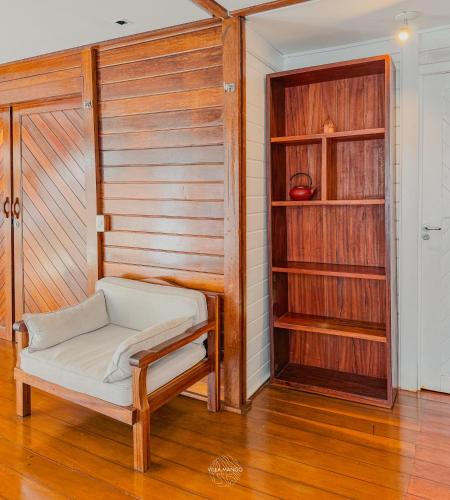 a room with a chair and a closet with wooden walls at Villa Mango in Icaraí