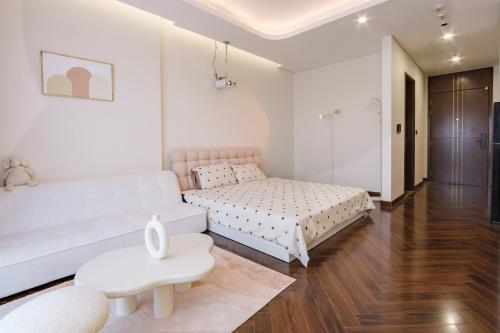 a white bedroom with a bed and a couch at Hapi Home in Hai Phong