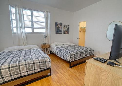 a room with two beds and a television in it at Miami Hallandale Condo, Partial Ocean View Direct Beach and Pool Access Miami Hollywood Beach in Hollywood