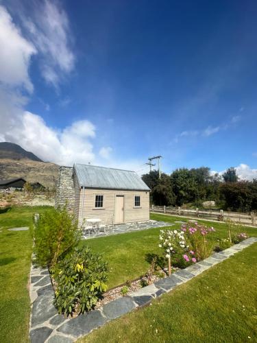 a barn with a garden and flowers in front of it at Hicks Cottage in Queenstown