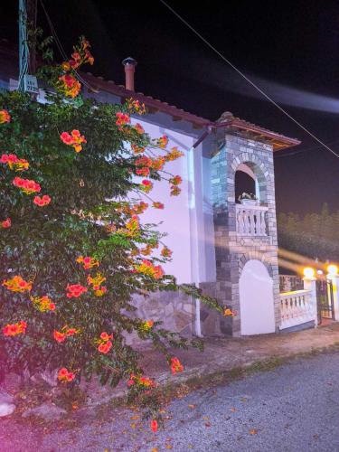 a small building with a bush with red flowers at Το Αρχοντικό Της Βέτας Στον Όλυμπο! in Pýthion