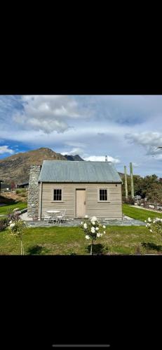 a small white house with a picnic table in front of it at Historical Hicks Cottage in Queenstown