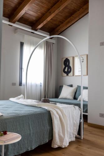 a white bedroom with a bed with a metal canopy at Villa Agavì in Marano sul Panaro