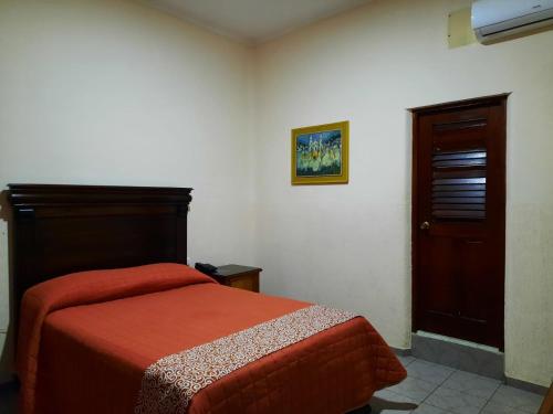 a bedroom with a bed with a red blanket at Hotel San Fernando Ciudad Valles in Ciudad Valles