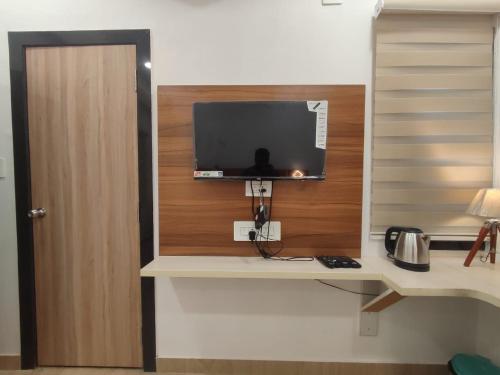 a room with a desk with a tv on a wall at THE TRIBHUVAN RESIDENCY 300 MTr FROM SHREE RAM MANDIR TAMPLE in Ayodhya