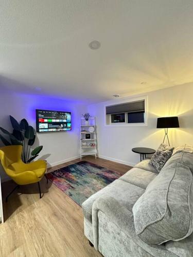 a living room with a couch and a tv at Stylish & Modern 2 Bedroom Suite in Regina