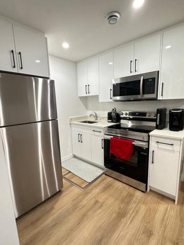 a kitchen with stainless steel appliances and white cabinets at Stylish & Modern 2 Bedroom Suite in Regina