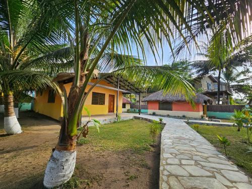 a palm tree in front of a house at Uzoma's Lodge in Butre