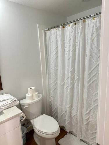 a bathroom with a toilet and a shower curtain at Stylish & Modern 2 Bedroom Suite in Regina