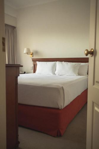 a bedroom with a large bed with white pillows at Austral Plaza Hotel in Comodoro Rivadavia