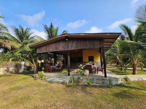 a small house with a porch with palm trees at Uzoma's Lodge in Butre