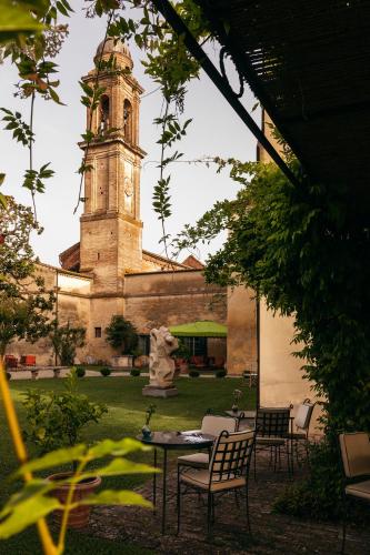 a building with a clock tower and a table and chairs at Hotel Certosa Di Maggiano in Siena