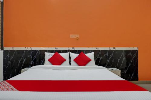 a bedroom with a bed with red and white pillows at Hotel O Sai Inn in Chinchiwad