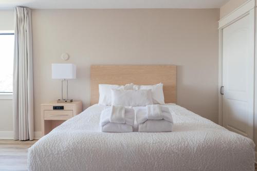 a bedroom with a white bed with white sheets and pillows at Kasa Gold Coast Inn Traverse City in Traverse City