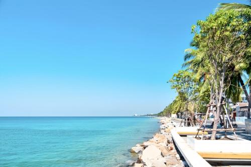 a beach with palm trees and the ocean at The Sunset Bangsaen Hotel in Ban Rong Khoei
