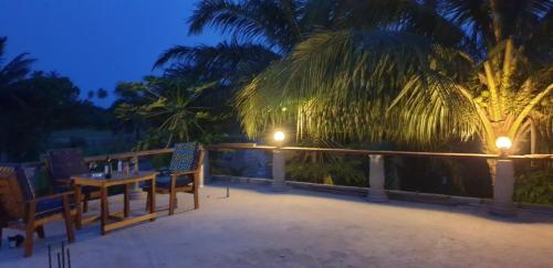 a deck with chairs and a table and a palm tree at Uzoma's Lodge in Butre