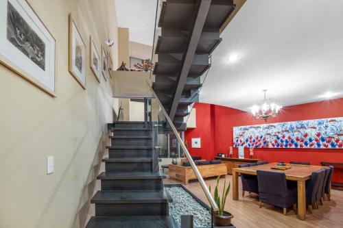 a staircase leading up to a dining room with a red wall at 3 BR Upscale Art House Reforma Avenue in Mexico City