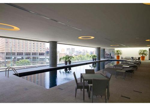 a restaurant with a swimming pool with tables and chairs at 3 BR Upscale Art House Reforma Avenue in Mexico City