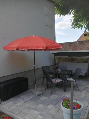 a red umbrella on a patio with chairs and a table at Ferienwohnung Poschmann in Bad Wilsnack