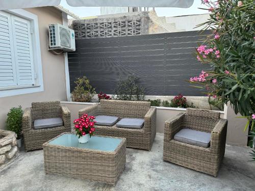 a patio with wicker chairs and a table with flowers at Sappir House in Pigadhákia