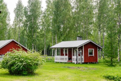 a red cabin in the middle of a field with trees at Patrikka Holiday Home in Ilomantsi