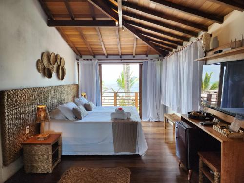 a bedroom with a white bed and a large window at Pousada Vila do Mar in Caraíva