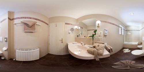 a bathroom with a tub and a sink and a mirror at Sporthotel Schönruh in Ehrwald