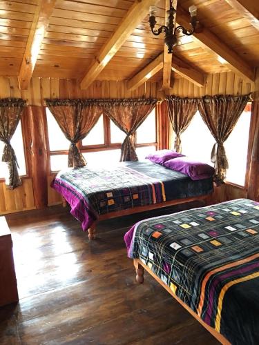 two beds in a room with wooden ceilings at Cabanas la puente in Mazamitla