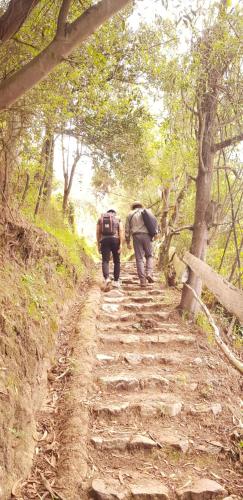 two people with backpacks walking down a dirt trail at Hacienda Jimenita Wildlife Reserve in Puembo