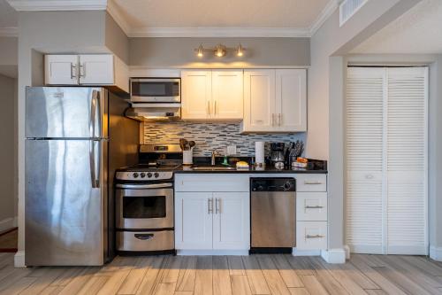 a kitchen with white cabinets and a stainless steel refrigerator at Emerald on the Water - Formerly Belleair Beach Club in Clearwater Beach